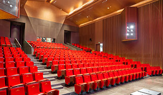 How to adjust the auditorium chairs to sit comfortably?