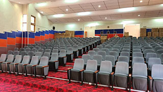 How should auditorium chairs made of different materials be maintained?